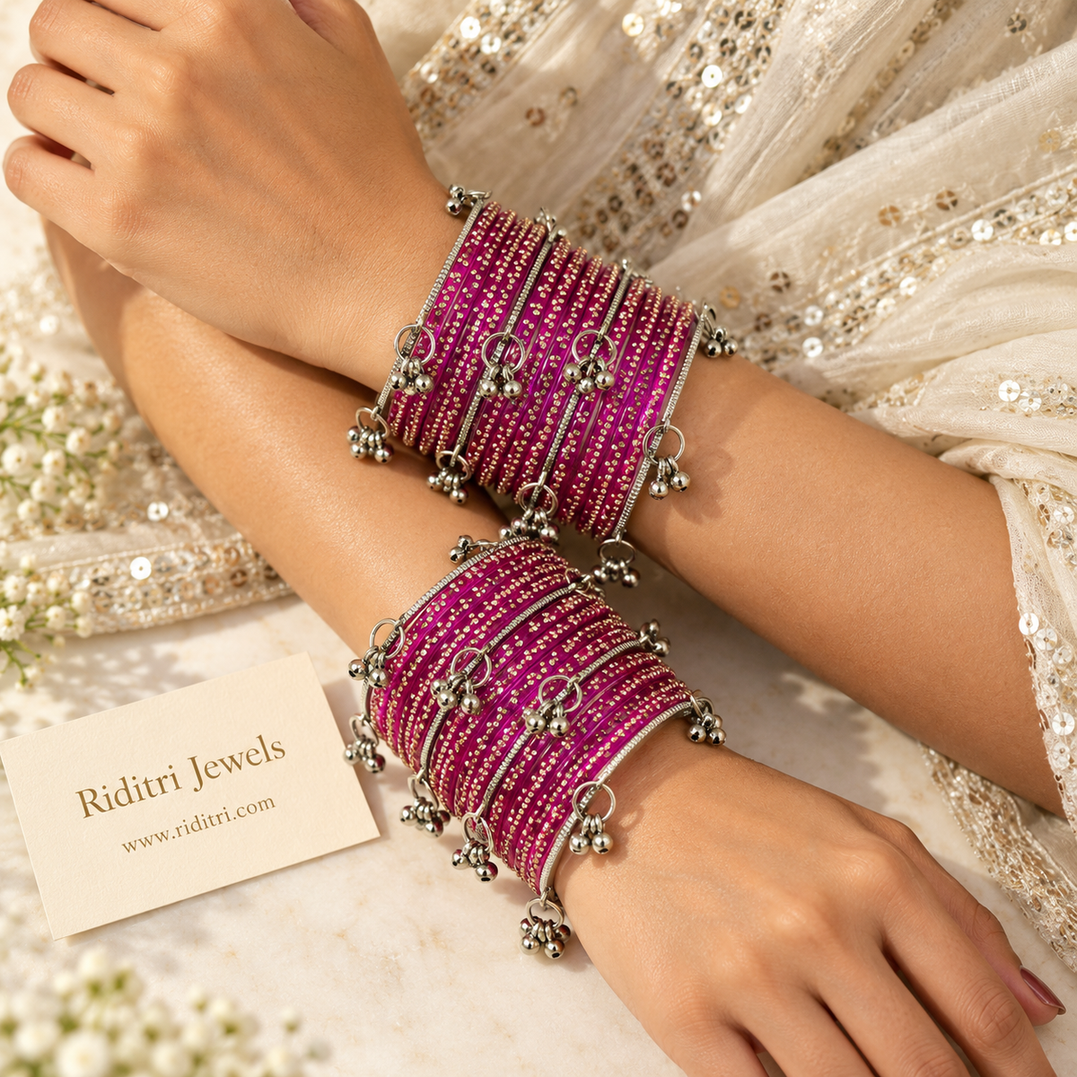 Rani pink glass bangles stacked with dangling silver ghungroo bells on display stand