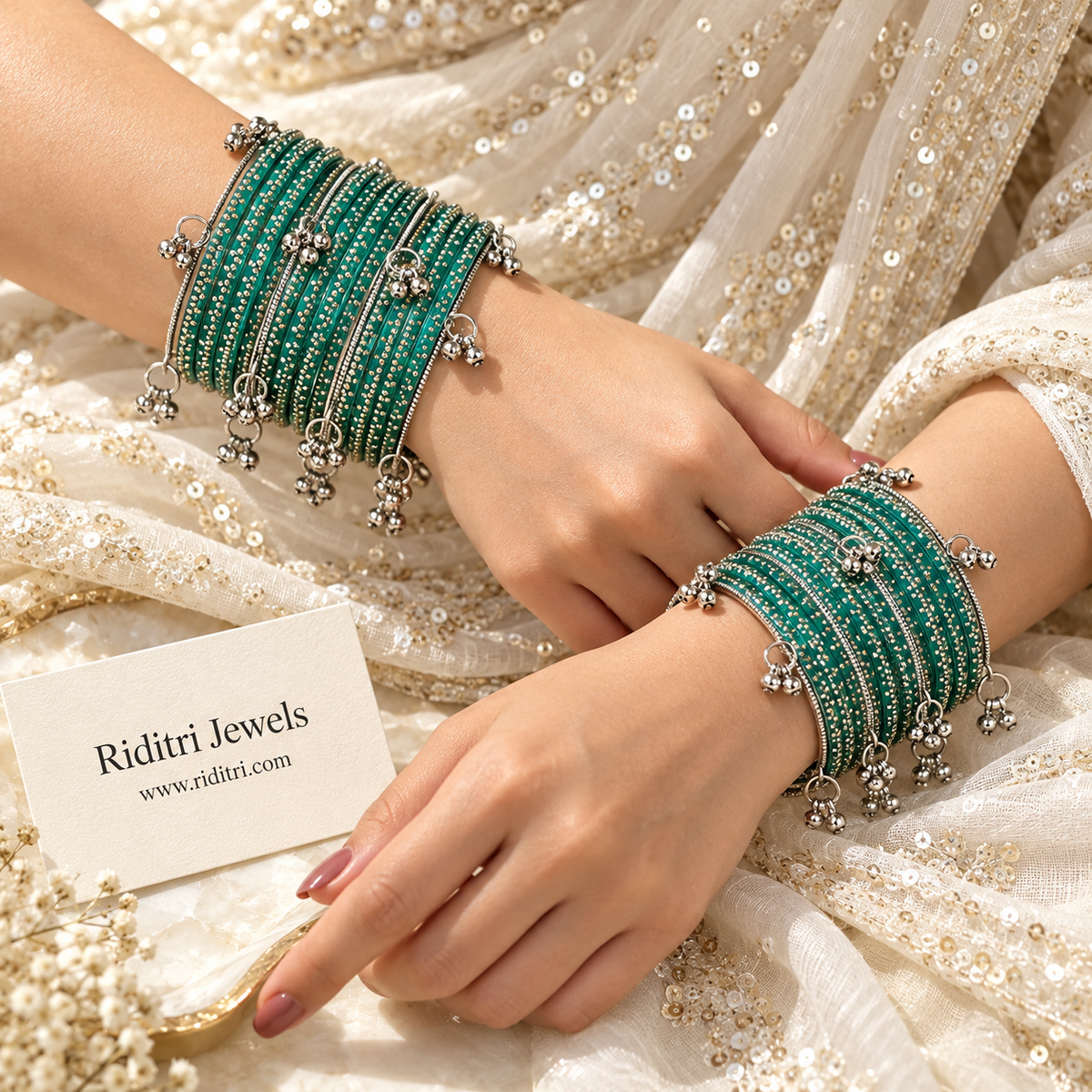Radium teal green glass bangles stacked with dangling silver ghungroo bells on display stand