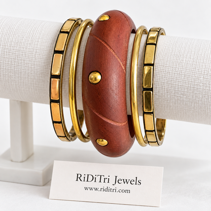 Vrinda bangle set of 5 with a carved reddish-brown wooden bangle with gold-toned studs, two segmented and two slim gold-toned bangles by Riditri