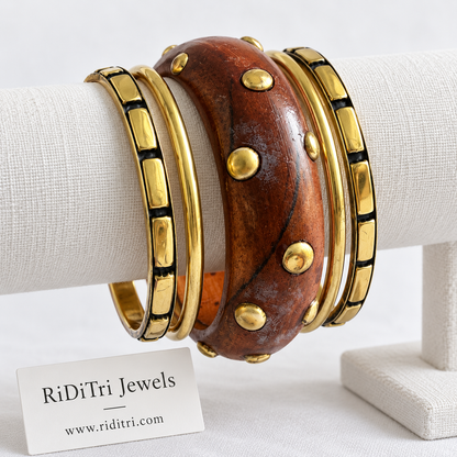Aranya bangle set of 5 with a chunky wooden bangle covered in gold-toned studs, two segmented gold-toned bangles and two slim gold-toned bangles by Riditri