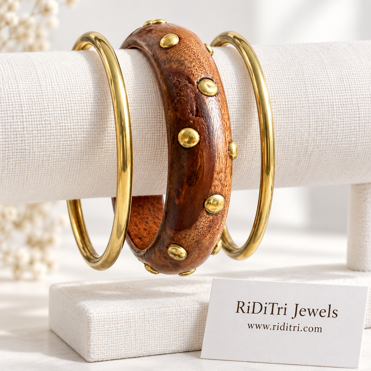 Vanika bangle set of 3 with a chunky wooden bangle covered in gold-toned studs between two slim gold-toned bangles by Riditri