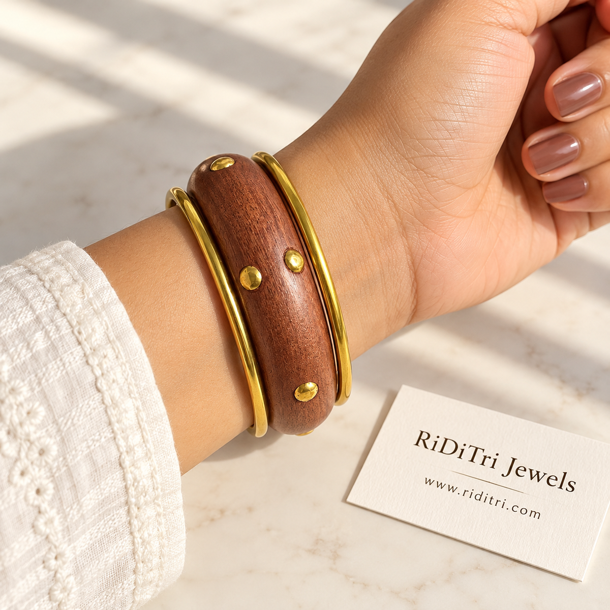 Kunj bangle set of 3 with a chunky wooden bangle with gold-toned studs between two slim gold-toned bangles by Riditri