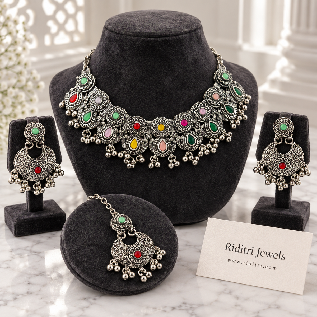 Navratan oxidised necklace set with multicolour stones, floral motifs and ghungroo drops, with matching chandbali earrings and maang tika by Riditri