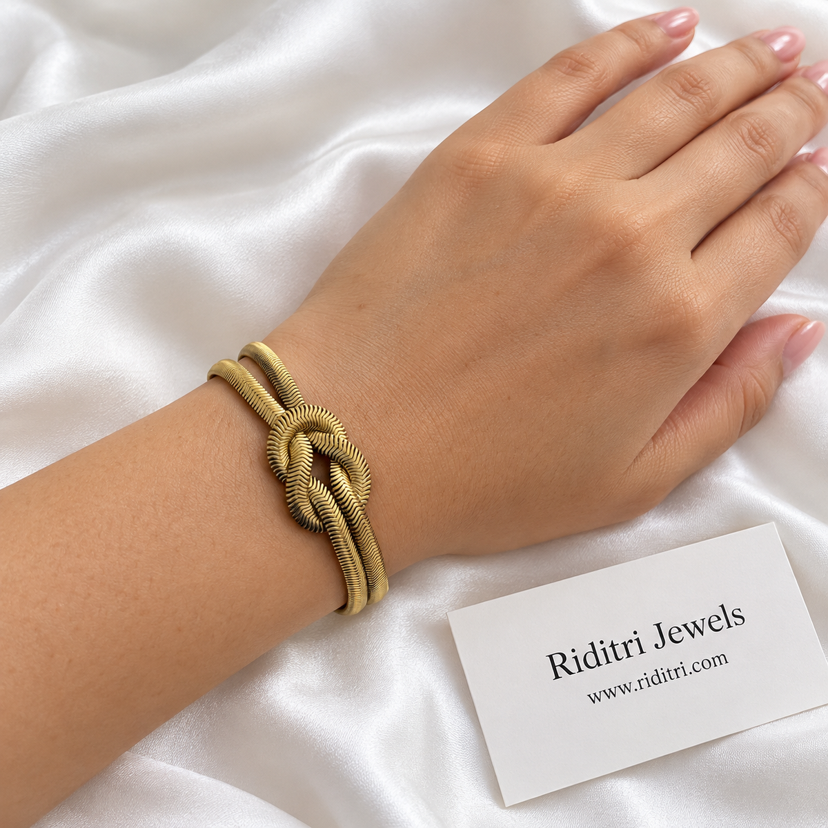 Anti Tarnish Love Knot Bracelet worn on the wrist – close-up of the gold-toned herringbone love knot, view 2