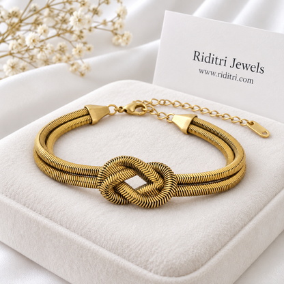 Anti tarnish stainless steel love knot bracelet with two bold gold-toned herringbone chains tied in a knot by Riditri