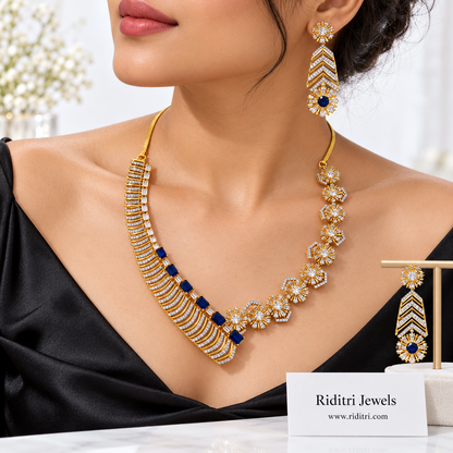 Gold-toned designer necklace with curved stone bars, blue rectangles and starburst flowers