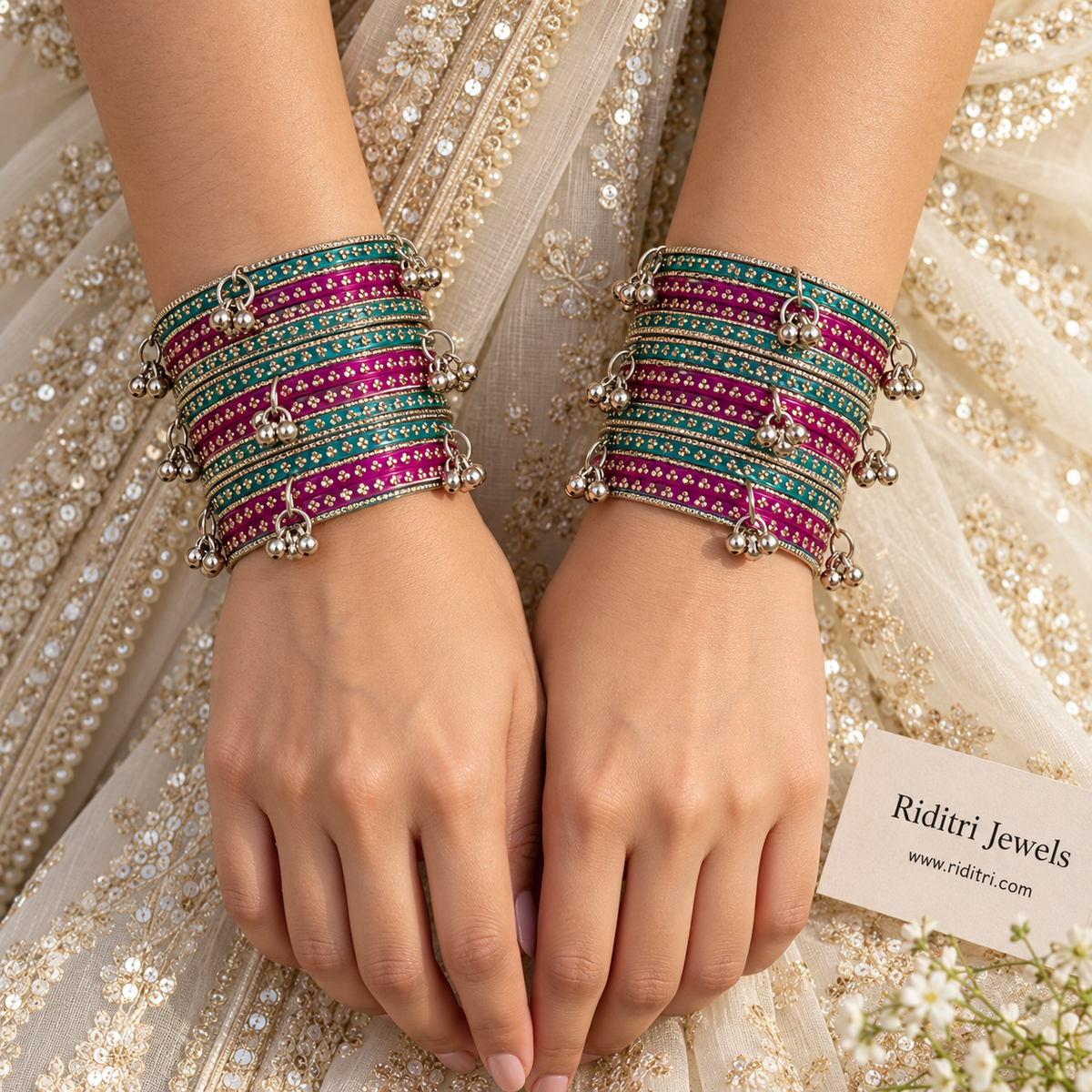 Rani pink and radium green glass bangles stacked with silver ghungroo bangles on display stand